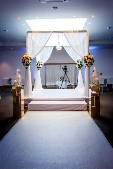 The chuppah, with flowers and a chandelier, in the Deal Hall at Kinloss